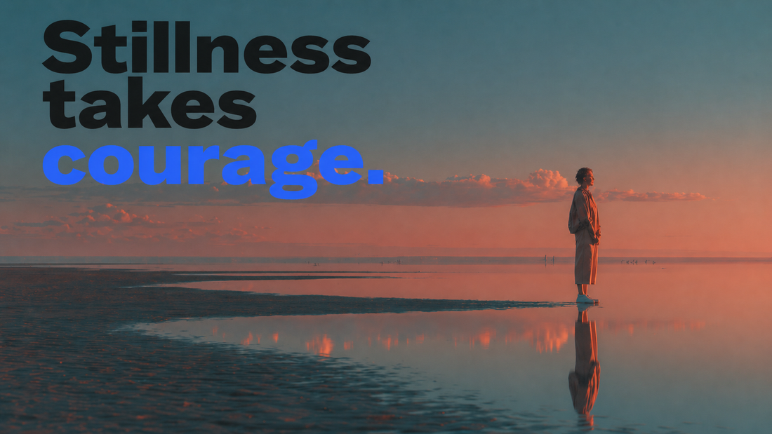 Stillness takes courage — a young woman stands at the edge of a glass-still tidal flat at sunset, her reflection mirrored perfectly in the wet sand beneath an immense peach and blue sky.